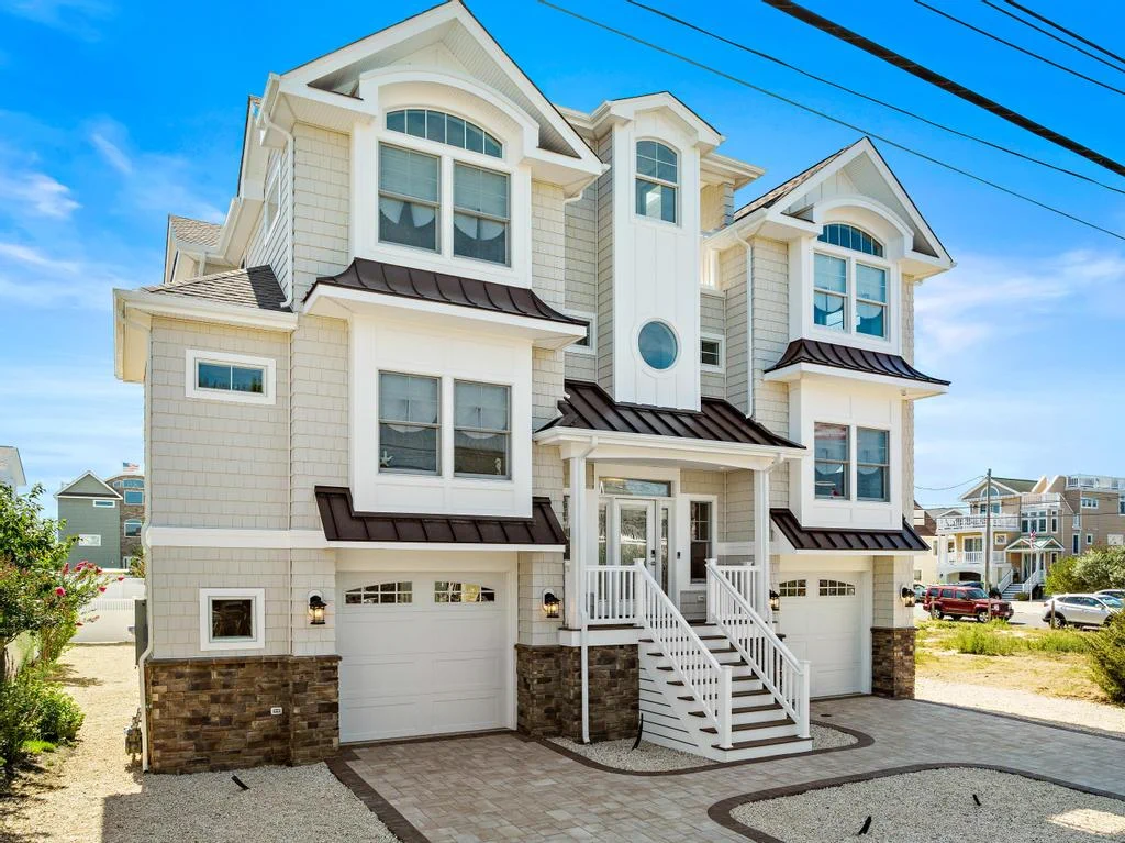 A modern, three-story beach house with a light-colored facade that had design build custom homes by JS Pro Property Management in long beach island, NJ
